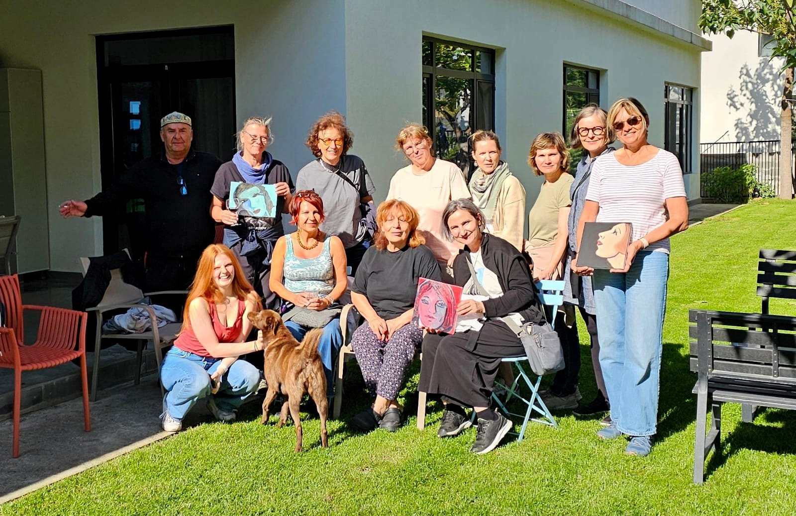 Gruppe der Frauenreise Georgien mit selbstgemalten Portraits im Garten des Ateliers der georgischen Künstlerin Lia Shvelidze in Saguramo, ein Hund mitten in der Gruppe