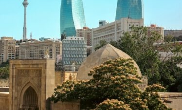 Luftaufnahme der drei Flammentürme in Baku bei Sonnenuntergang mit goldenem Licht über der Stadt