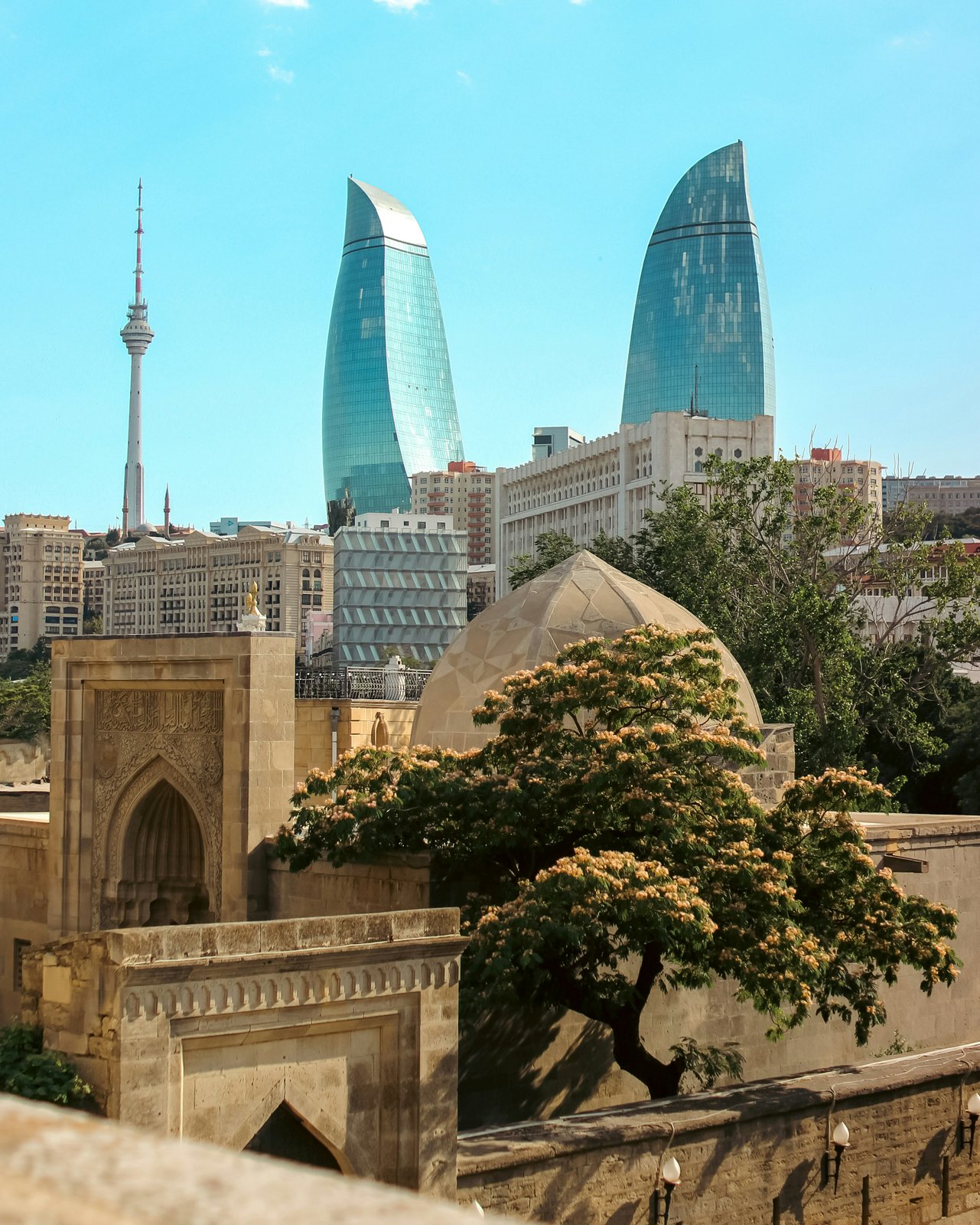 Luftaufnahme der drei Flammentürme in Baku bei Sonnenuntergang mit goldenem Licht über der Stadt