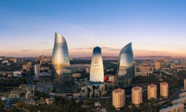 Mittelalterliche Altstadt Icheri Sheher in Baku mit den modernen Flammentürmern im Hintergrund und blauem Himmel