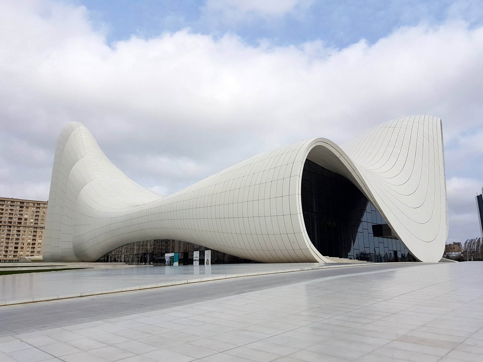 Das weiße geschwungene Heydar Aliyev Center in Baku, entworfen von Zaha Hadid, vor bewölktem Himmel