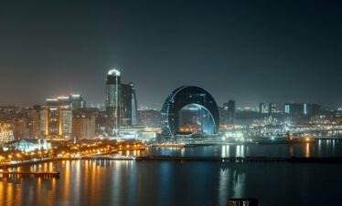 Baku Skyline bei Nacht mit dem runden Baku Eye Gebäude und Stadtlichtern gespiegelt im Kaspischen Meer