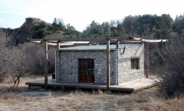 Rustikaler Steinbungalow mit Holzterrasse und Pergola in der Wildnis der Rangerstation Mijnis Kure im Nationalpark Vashlovani, Georgien