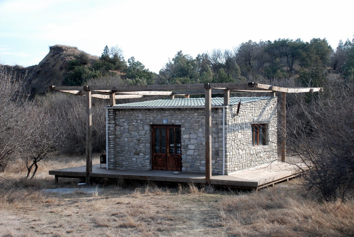 Rustikaler Steinbungalow mit Holzterrasse und Pergola in der Wildnis der Rangerstation Mijnis Kure im Nationalpark Vashlovani, Georgien