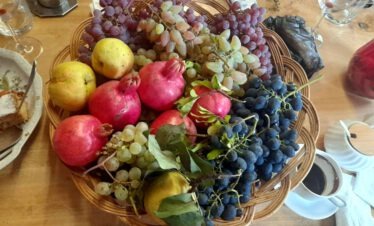 Ein geflochtener Korb voll frischer georgischer Früchte wie Granatäpfel, Weintrauben und Quitten.