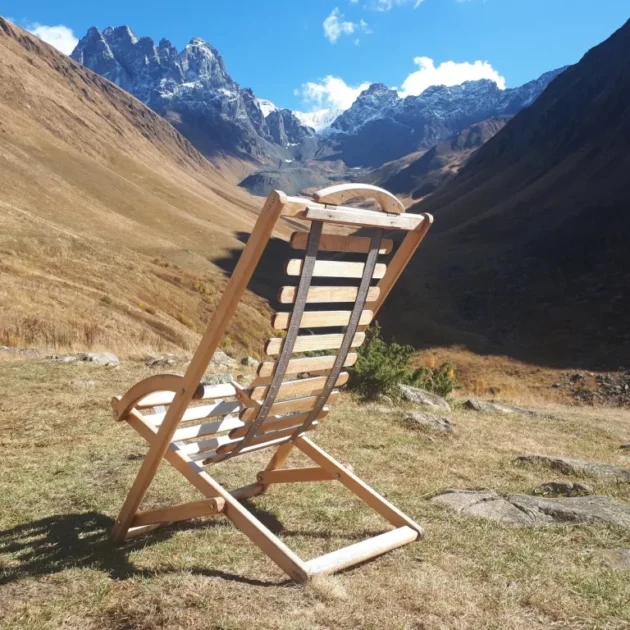 Ein einsamer Holzstuhl blickt ins weite Tschauchi-Tal mit schneebedeckten Gipfeln des Großen Kaukasus bei Dschuta