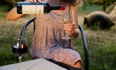 Eine Frau schenkt im warmen Abendlicht georgischen Wein auf einer Terrasse ein.