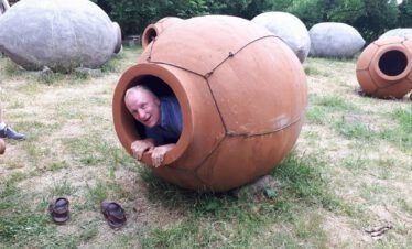 Ein lachender Tourist schaut aus einer großen, traditionellen georgischen Wein-Amphore (Qvevri).