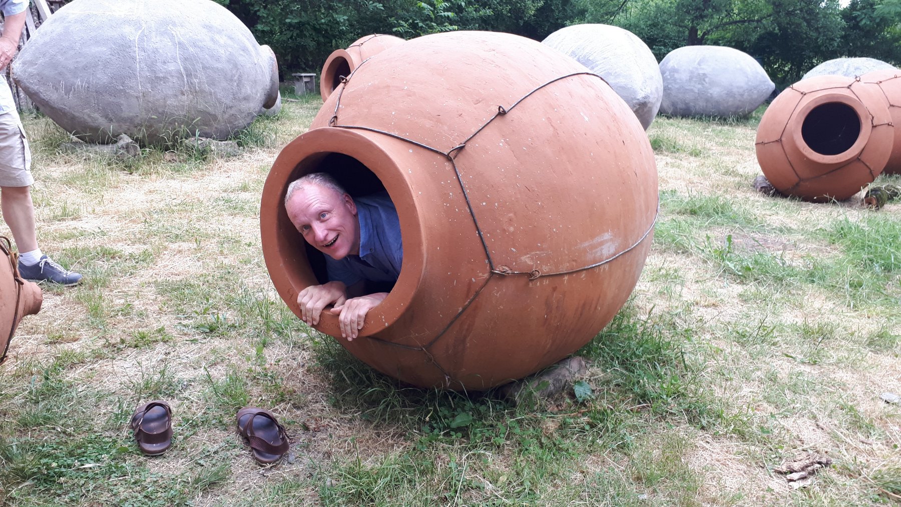 Ein lachender Tourist schaut aus einer großen, traditionellen georgischen Wein-Amphore (Qvevri).