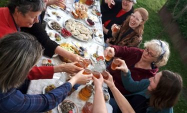 Blick von oben auf eine reich gedeckte georgische Tafel mit Khachapuri, Salaten und Wein.