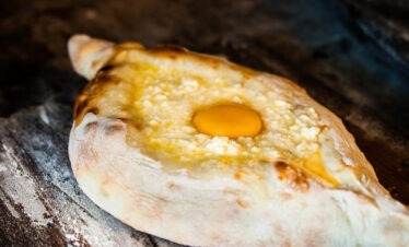 Ofenfrisches Adscharisches Chatschapuri mit Käse und Ei als Teil eines traditionellen georgischen Frühstücks.