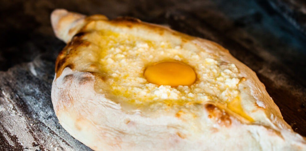Ofenfrisches Adscharisches Chatschapuri mit Käse und Ei als Teil eines traditionellen georgischen Frühstücks.