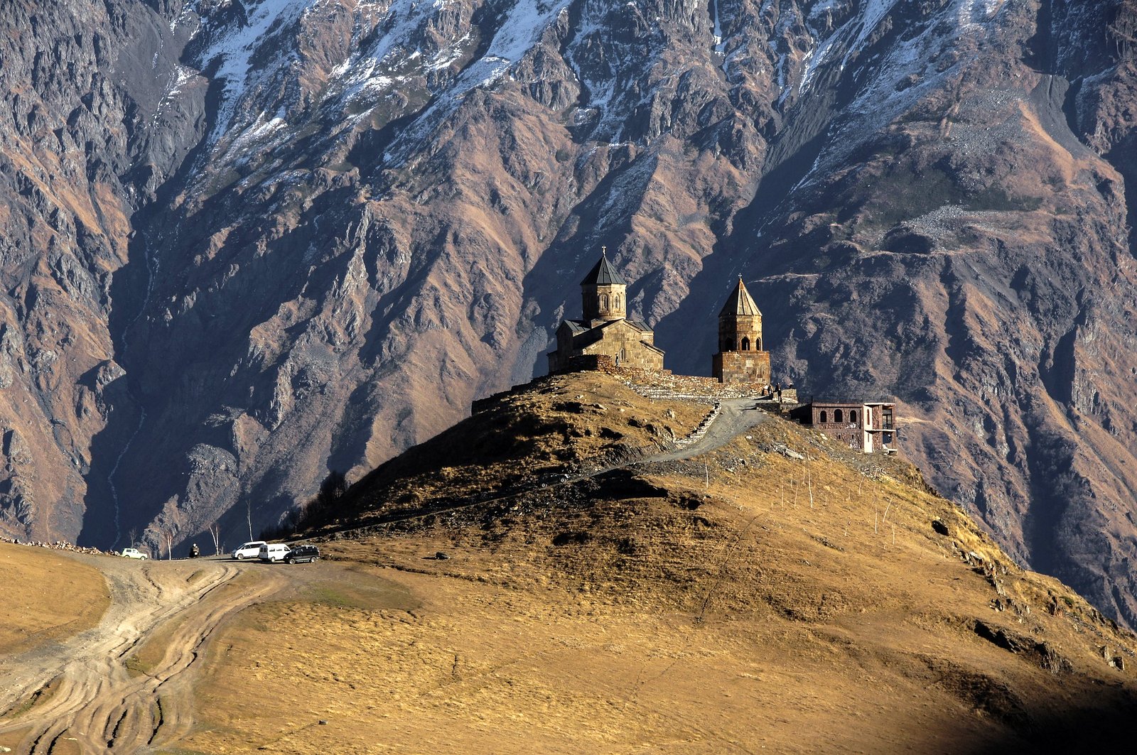 Die Sameba-Gergeti Dreifaltigkeitskirche auf einem Bergrücken vor der massiven Felswand des Kaukasus.