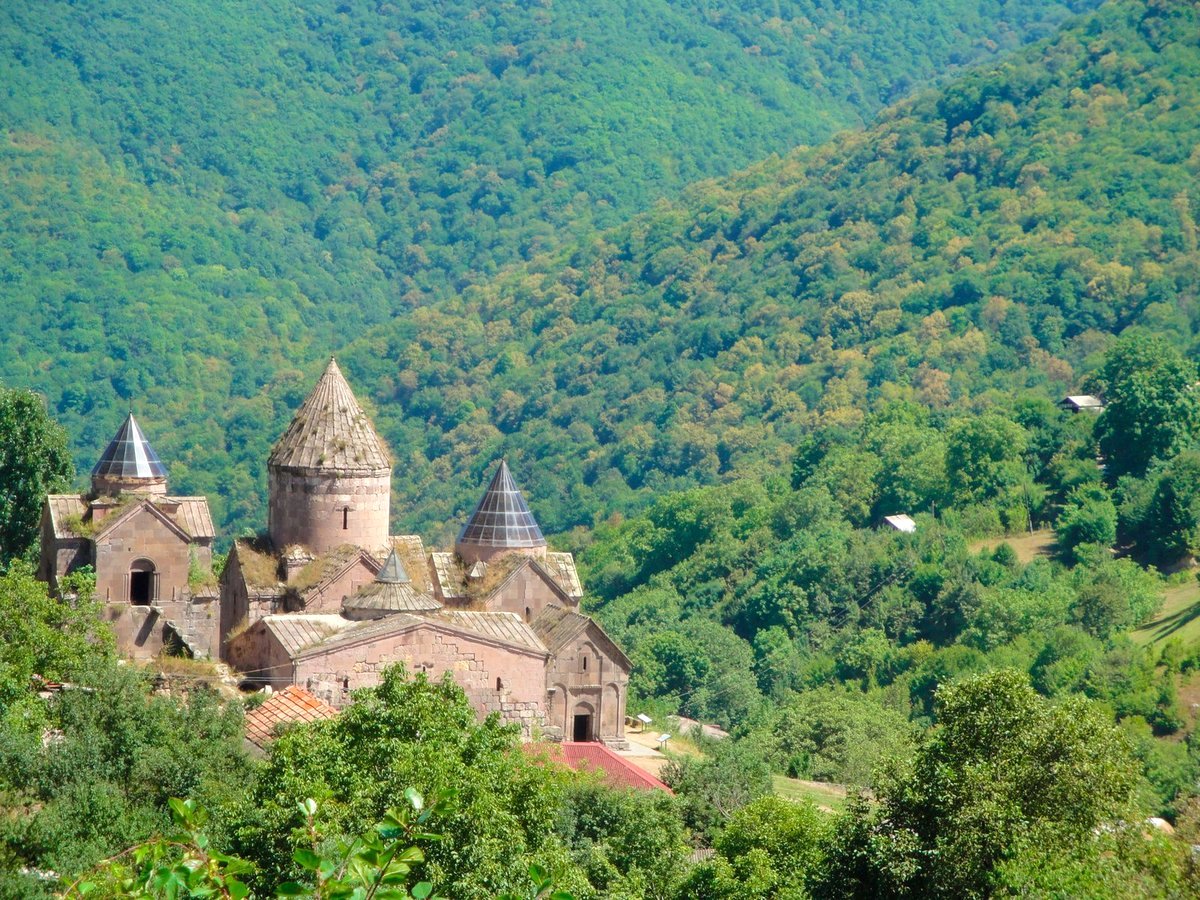 Das mittelalterliche Kloster Goshavank aus rosa Tuffstein mit drei Kirchtürmen eingebettet in dichten grünen Wald bei Dilidjan Armenien