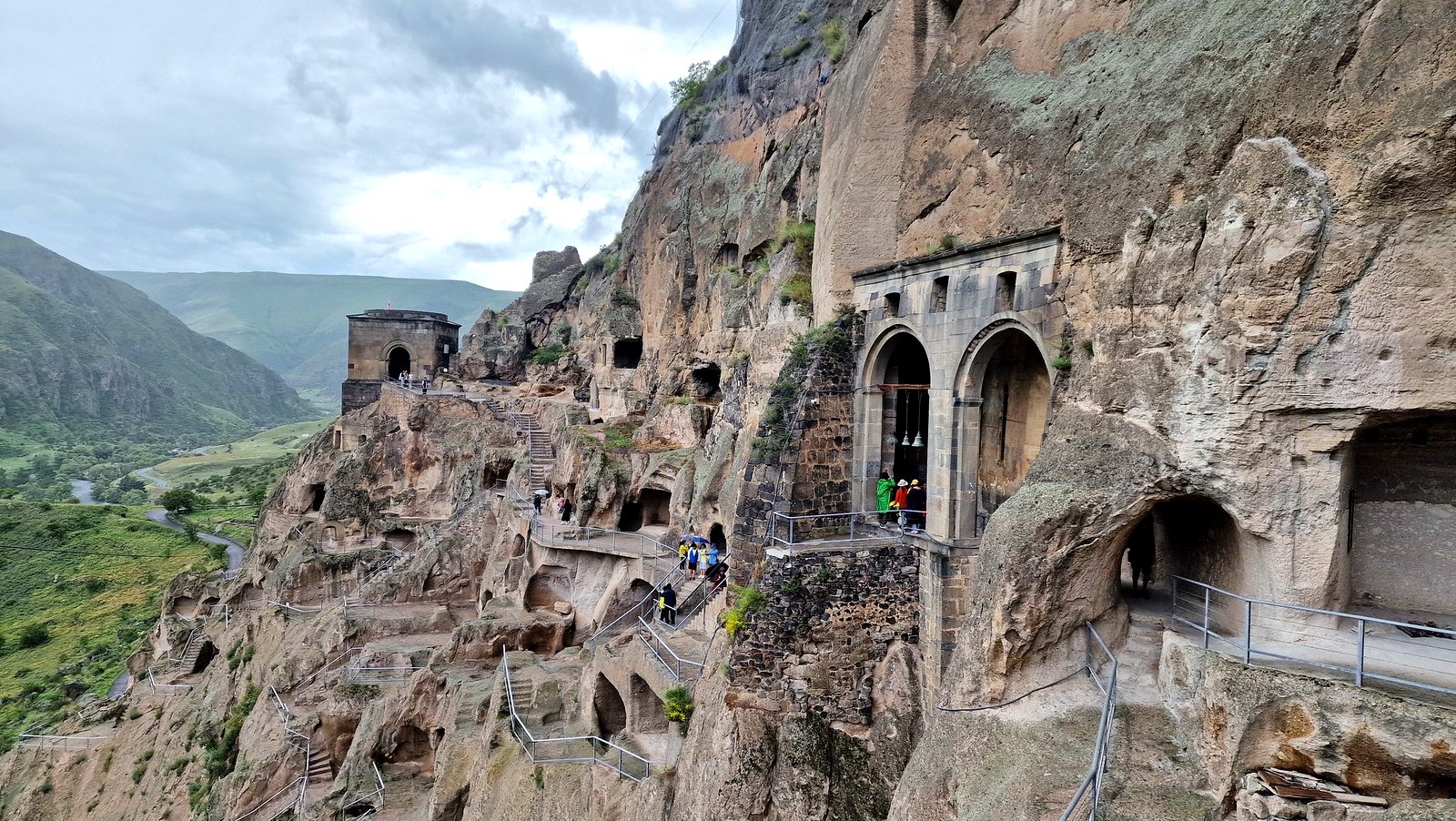 Blick auf die in den Fels gehauenen Höhlen, Treppen und Bogengänge der mittelalterlichen Höhlenstadt Wardsia im grünen Canyon des Mtkwari-Flusses in Südgeorgien