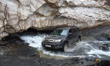 Toyota 4x4 durchquert Wildbach unter Schneebogen – Offroad Georgien