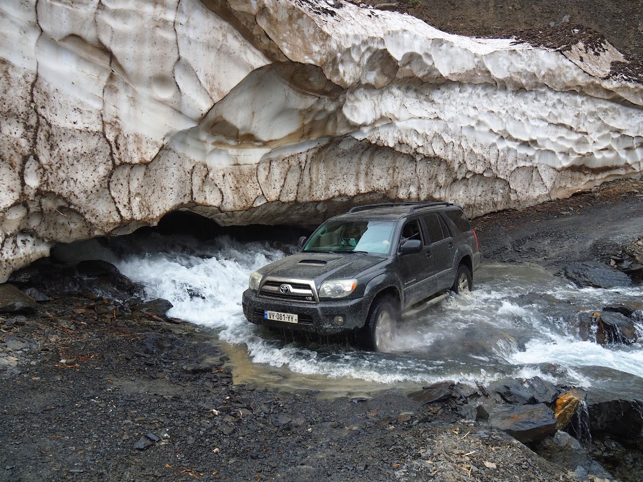 Toyota 4x4 durchquert Wildbach unter Schneebogen – Offroad Georgien
