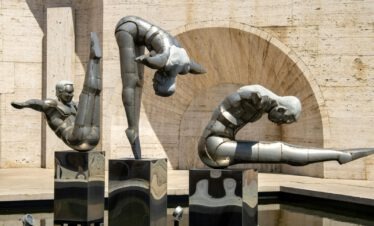 Drei akrobatische Metallskulpturen in einem Wasserbecken vor Travertin-Architektur in Jerewan Armenien