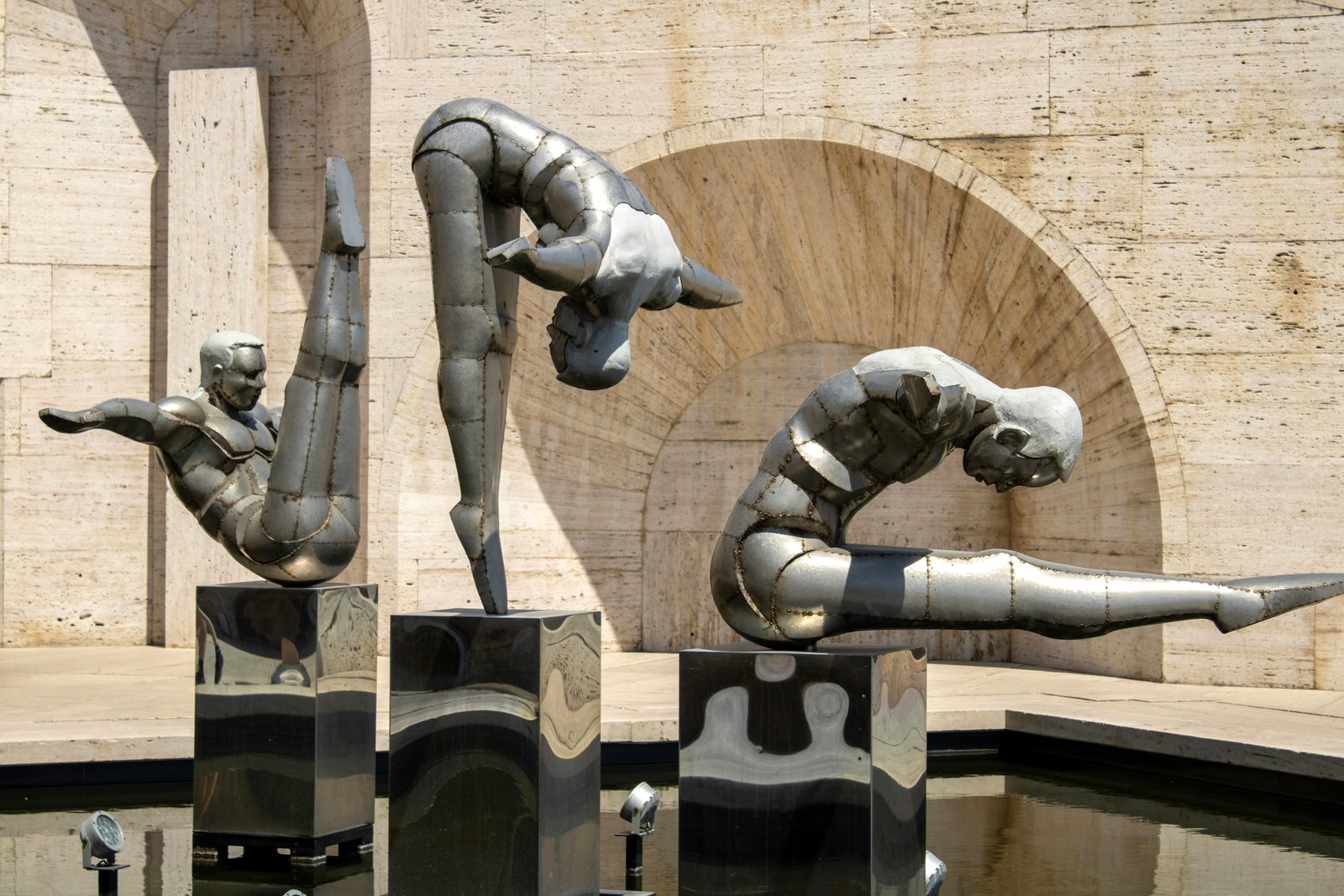 Drei akrobatische Metallskulpturen in einem Wasserbecken vor Travertin-Architektur in Jerewan Armenien