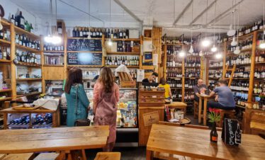 Rustikale Weinbar In Vino in Jerewan Armenien mit Holzregalen voller Weinflaschen und Gästen an Tischen