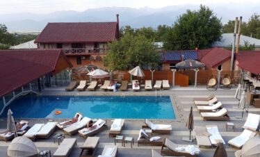 Pool mit Liegestühlen eines Weingut-Hotels in Kachetien, im Hintergrund die schneebedeckten Gipfel des Großen Kaukasus, Georgien