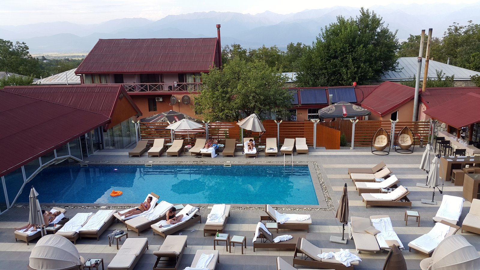 Pool mit Liegestühlen eines Weingut-Hotels in Kachetien, im Hintergrund die schneebedeckten Gipfel des Großen Kaukasus, Georgien