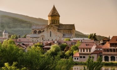 Die Swetizchoweli Kathedrale in Mzcheta Georgien im goldenen Abendlicht mit dem Fluss Mtkvari und grünen Bergen im Hintergrund