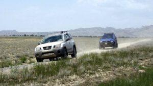 Zwei Nissan Xterra Mietwagen fahren auf einer Schotterpiste durch die weite Steppe in Georgien.