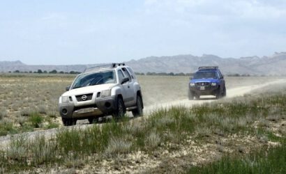 Zwei Nissan Xterra Mietwagen fahren auf einer Schotterpiste durch die weite Steppe in Georgien.