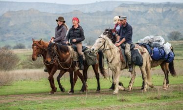 Reitergruppe auf tuschetischen Pferden vor den markanten Sandstein-Tafelbergen des Nationalparks Vashlovani, Georgien