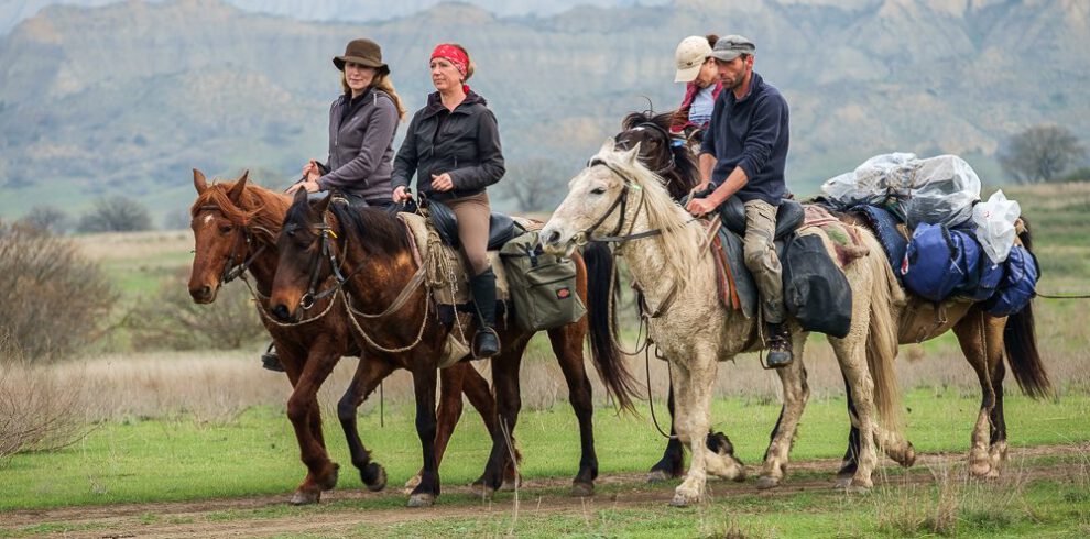 Reitergruppe auf tuschetischen Pferden vor den markanten Sandstein-Tafelbergen des Nationalparks Vashlovani, Georgien