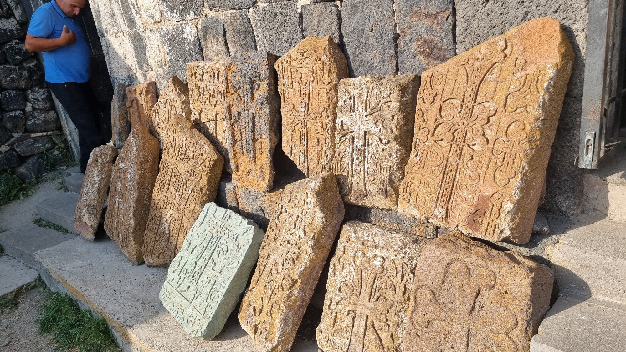 Mehrere armenische Khachkare aus orangefarbenem Tuffstein mit filigranen Kreuzornamenten am Kloster Sevanavank
