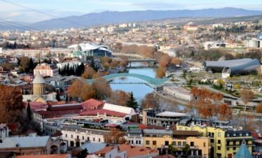 Weitwinkel-Blick über die Altstadt von Tiflis mit der modernen Friedensbrücke und dem Kura-Fluss.