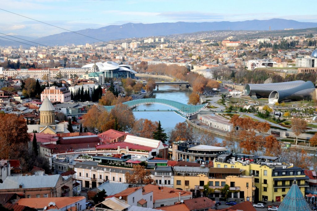 Weitwinkel-Blick über die Altstadt von Tiflis mit der modernen Friedensbrücke und dem Kura-Fluss.