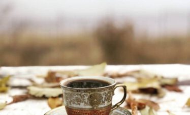 Antike armenische Kaffeetasse auf einem verwitterten Tisch mit Herbstblättern, Armenien