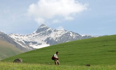Dr. Hans Jürgen Buhr bei der botanischen Exkursion auf einer Almwiese im Großen Kaukasus mit Blick auf den Kasbek, Georgien