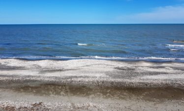 Flacher Kiesstrand am Kaspischen Meer unter blauem Himmel, Aserbaidschan