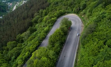 Luftaufnahme einer Serpentinenstraße durch dichten grünen Buchenwald im Nationalpark Dilidschan, Armenien