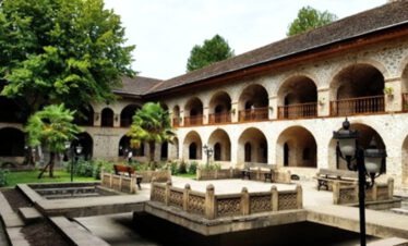 Innenhof einer historischen Karawanserei in Sheki mit Arkaden und Springbrunnen, Aserbaidschan
