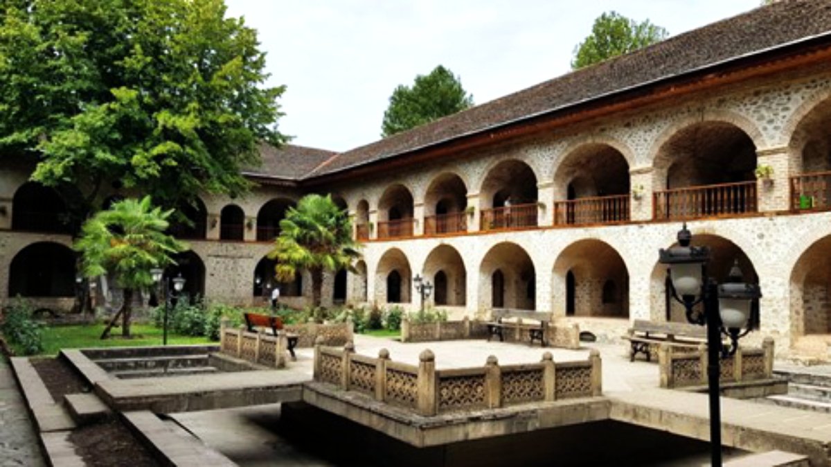 Innenhof einer historischen Karawanserei in Sheki mit Arkaden und Springbrunnen, Aserbaidschan