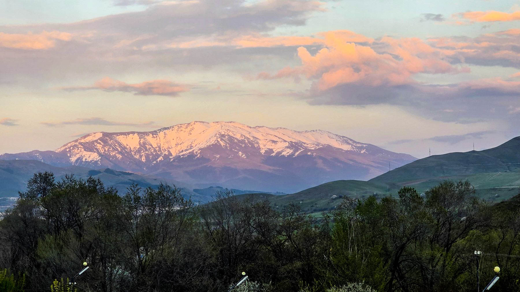 Snowy Armenian mountains at sunset with soft pink clouds