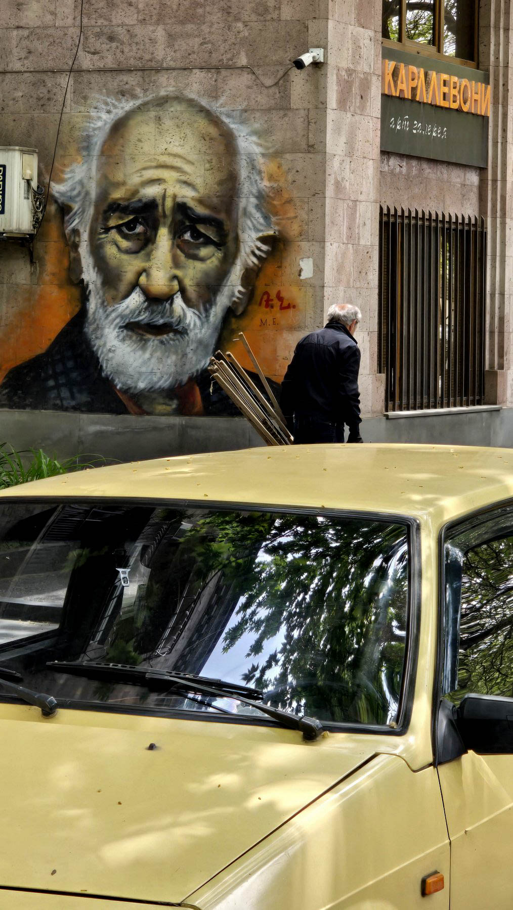Street mural of Sayat-Nova beside an old car in Yerevan