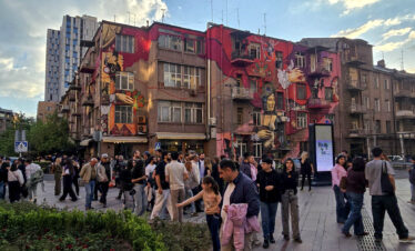 Busy evening street scene in central Yerevan with murals and pedestrians